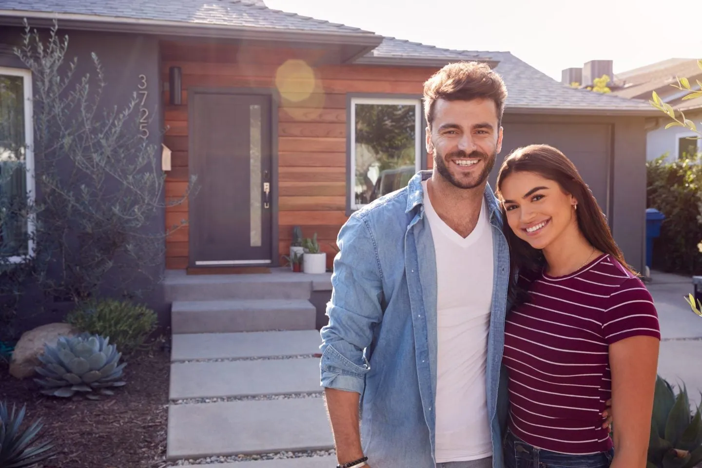 Smiling couple standing in front of their home
